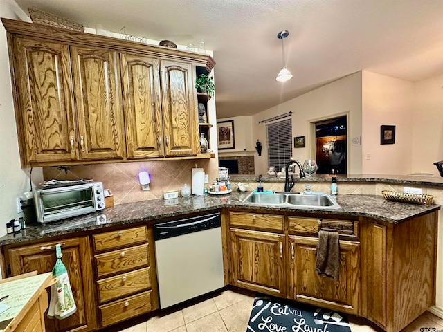 kitchen featuring sink, kitchen peninsula, dark stone counters, dishwasher, and decorative backsplash