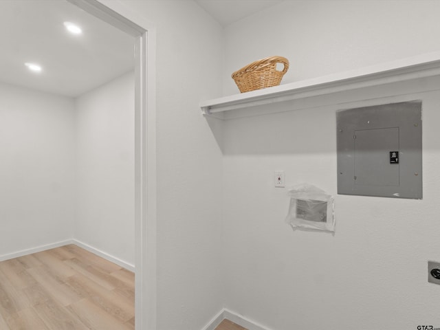 clothes washing area with electric panel, light hardwood / wood-style flooring, and electric dryer hookup