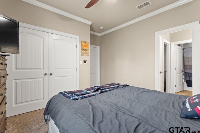 carpeted bedroom with ceiling fan, crown molding, and a closet