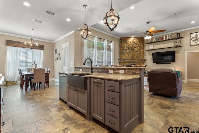 kitchen with light stone countertops, ceiling fan with notable chandelier, a healthy amount of sunlight, and decorative light fixtures