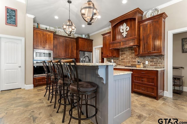 kitchen featuring light stone countertops, stainless steel appliances, an inviting chandelier, a breakfast bar area, and a kitchen island with sink