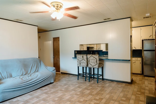 living room with ceiling fan and ornamental molding