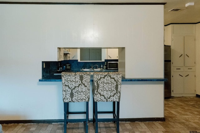 kitchen with decorative backsplash, sink, and white cabinetry