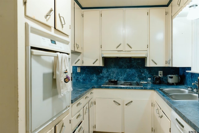 kitchen with decorative backsplash, sink, white appliances, and white cabinets