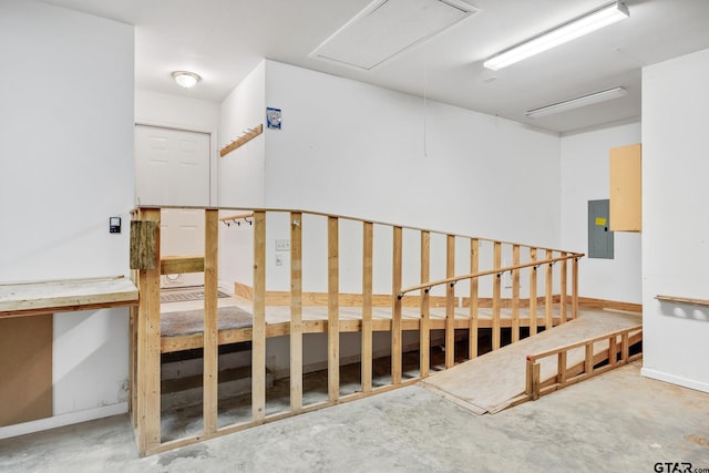 staircase featuring electric panel and concrete floors