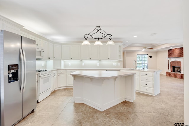 kitchen featuring pendant lighting, white appliances, ceiling fan, a kitchen island, and kitchen peninsula