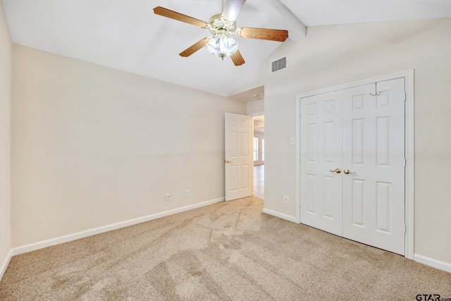 unfurnished bedroom with vaulted ceiling with beams, ceiling fan, a closet, and light colored carpet