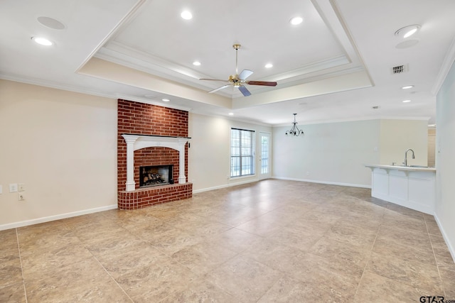 unfurnished living room with a fireplace, ceiling fan with notable chandelier, a raised ceiling, and crown molding