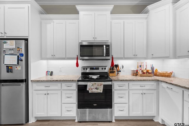 607 Main St, Bullard, TX 75757 - kitchen with appliances with stainless steel finishes, decorative backsplash, white cabinetry, light stone counters, and crown molding