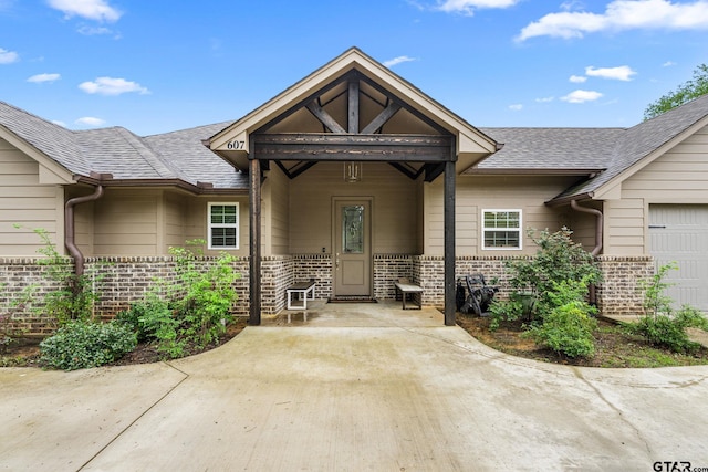 607 Main St, Bullard, TX 75757 - view of exterior entry featuring brick siding, a shingled roof, and an attached garage