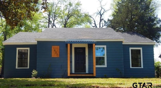 bungalow-style home with a front lawn and roof with shingles