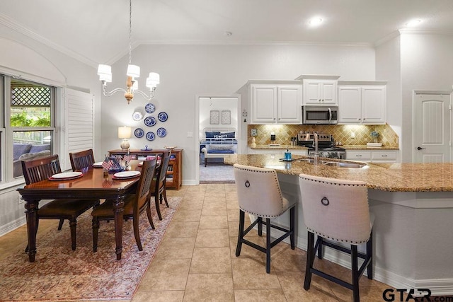 4133 Colina Trl, Tyler, TX 75707 - kitchen with appliances with stainless steel finishes, light stone countertops, ornamental molding, tasteful backsplash, and a kitchen bar