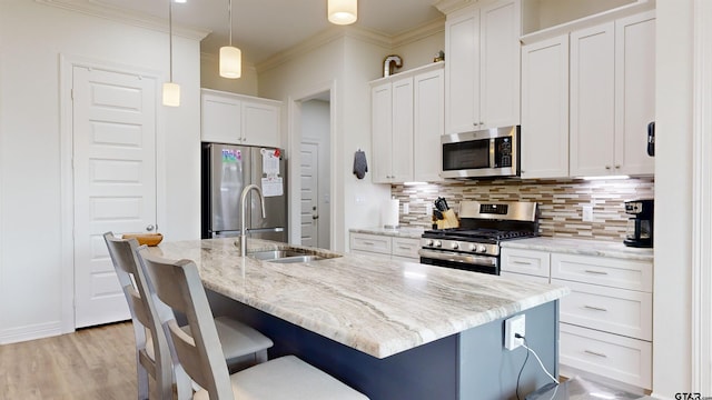 kitchen featuring decorative backsplash, hanging light fixtures, appliances with stainless steel finishes, and a kitchen island with sink