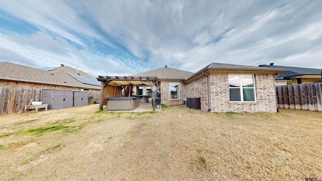 rear view of house with a pergola, central AC, a yard, and a hot tub