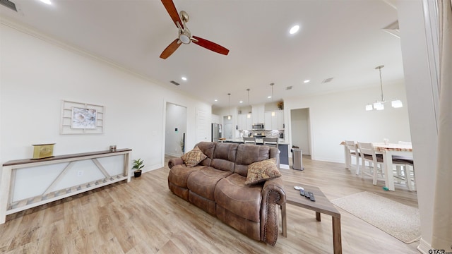 living room featuring ceiling fan with notable chandelier, light hardwood / wood-style flooring, and ornamental molding