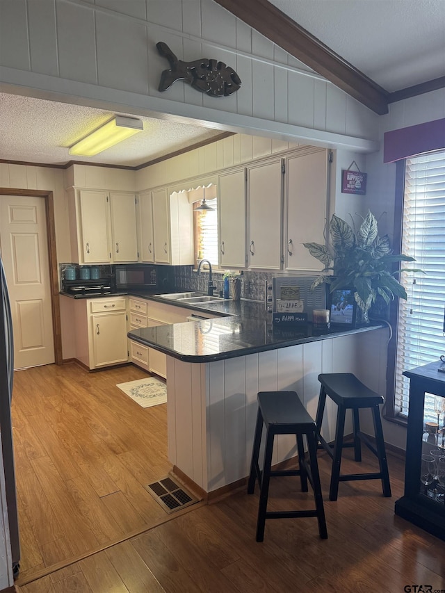 kitchen featuring ornamental molding, light hardwood / wood-style floors, kitchen peninsula, and white cabinets