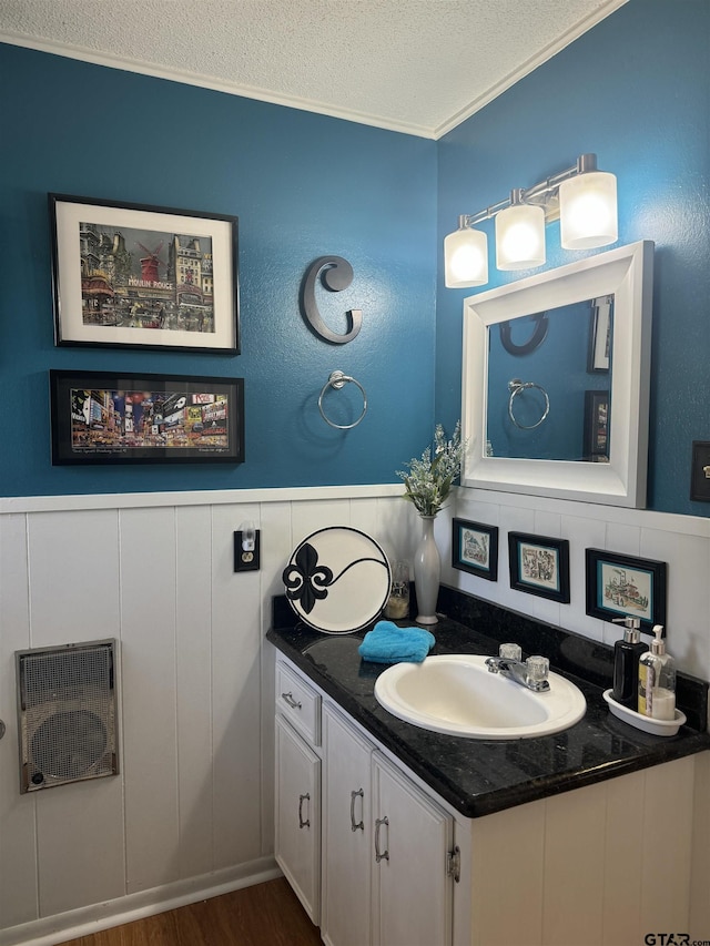 bathroom with vanity, hardwood / wood-style floors, ornamental molding, and a textured ceiling