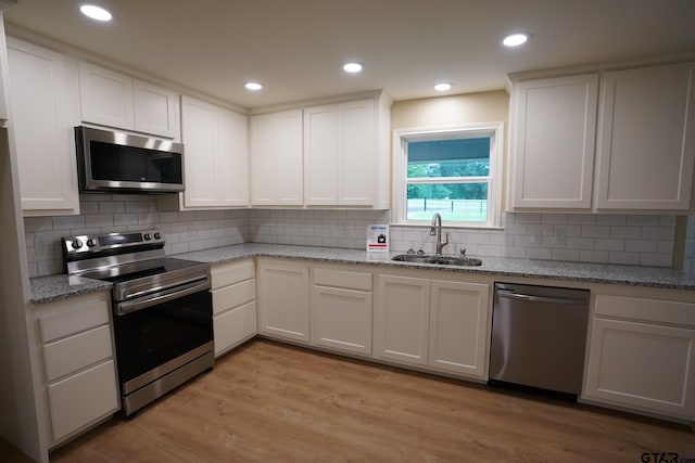 1370 Fm 315, Palestine, TX 75801 - kitchen with stainless steel appliances, a sink, white cabinets, light wood-style flooring, and decorative backsplash