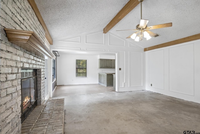 unfurnished living room featuring lofted ceiling with beams, a textured ceiling, concrete floors, a decorative wall, and a brick fireplace