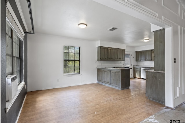 kitchen with light wood finished floors, baseboards, dishwasher, light countertops, and a peninsula