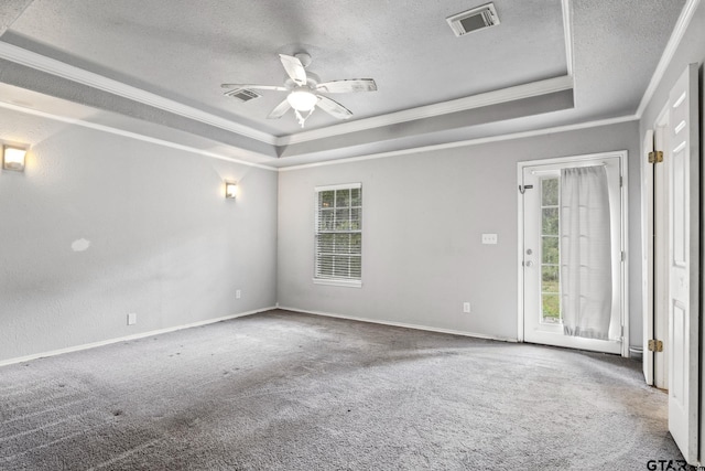 carpeted spare room with visible vents, a textured ceiling, and a tray ceiling