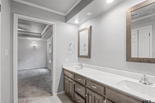 bathroom with a sink, double vanity, crown molding, and a textured wall