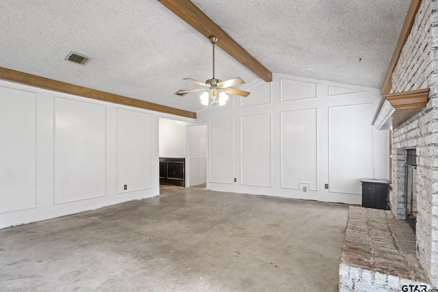 unfurnished living room with visible vents, vaulted ceiling with beams, a textured ceiling, a brick fireplace, and a decorative wall