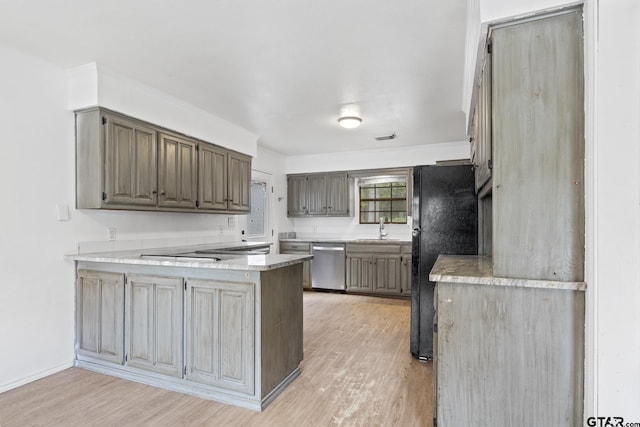 kitchen featuring a peninsula, stainless steel dishwasher, freestanding refrigerator, light wood-style floors, and a sink