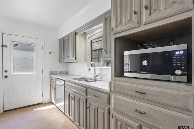 kitchen featuring light stone counters, light wood-style floors, appliances with stainless steel finishes, and a sink