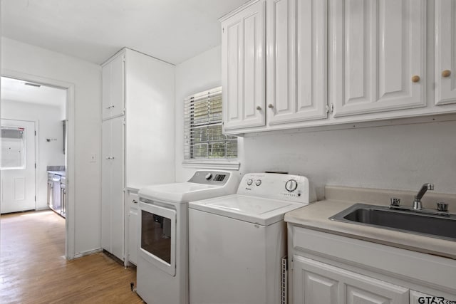 laundry area with light wood finished floors, visible vents, washer and clothes dryer, cabinet space, and a sink