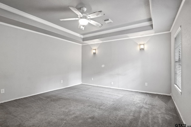 carpeted empty room featuring a tray ceiling, crown molding, visible vents, and ceiling fan