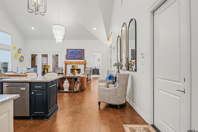 kitchen featuring light stone counters, stainless steel dishwasher, dark hardwood / wood-style floors, a chandelier, and pendant lighting