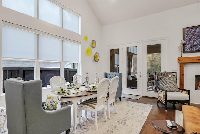 dining area featuring dark hardwood / wood-style flooring, lofted ceiling, a tiled fireplace, and french doors