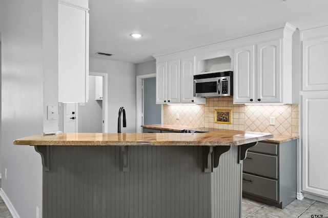 kitchen featuring white cabinetry, a kitchen breakfast bar, and kitchen peninsula