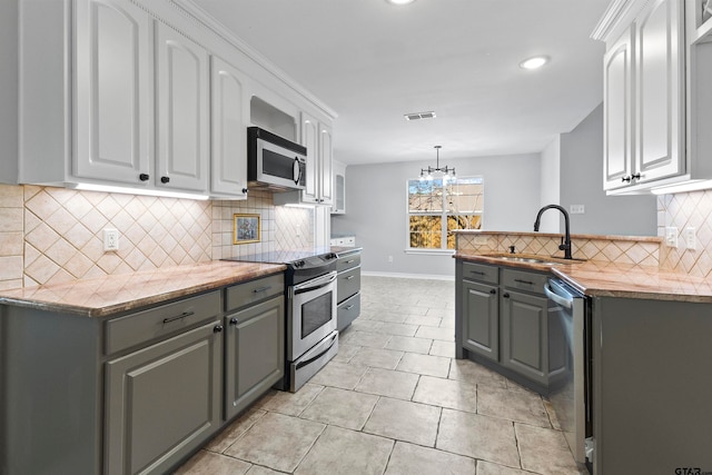 kitchen featuring stainless steel appliances, gray cabinets, white cabinetry, and sink