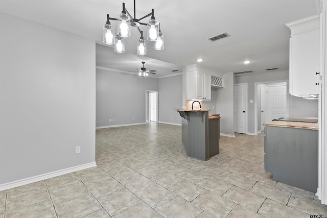 kitchen featuring wooden counters, decorative light fixtures, white cabinets, a breakfast bar area, and ceiling fan with notable chandelier