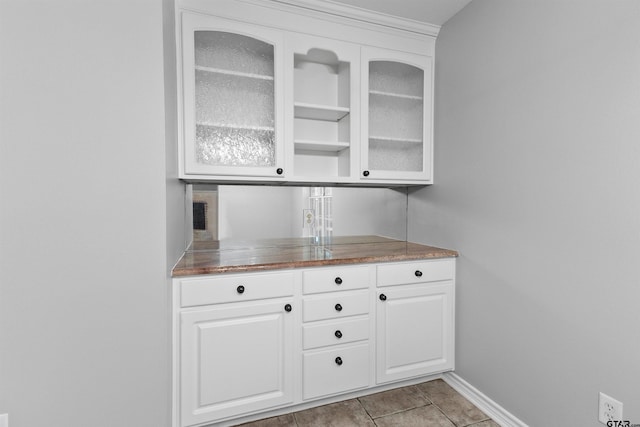 bar featuring light tile patterned flooring and white cabinetry