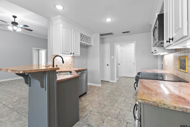 kitchen with sink, a breakfast bar, appliances with stainless steel finishes, white cabinets, and decorative backsplash