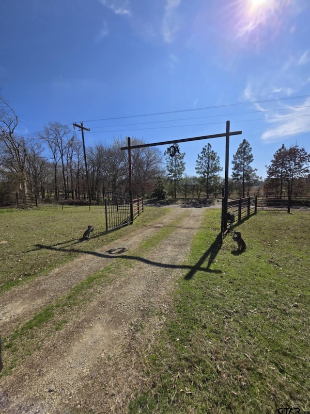 view of yard featuring dirt driveway, fence, and a rural view