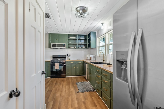 kitchen with open shelves, backsplash, appliances with stainless steel finishes, a sink, and green cabinetry