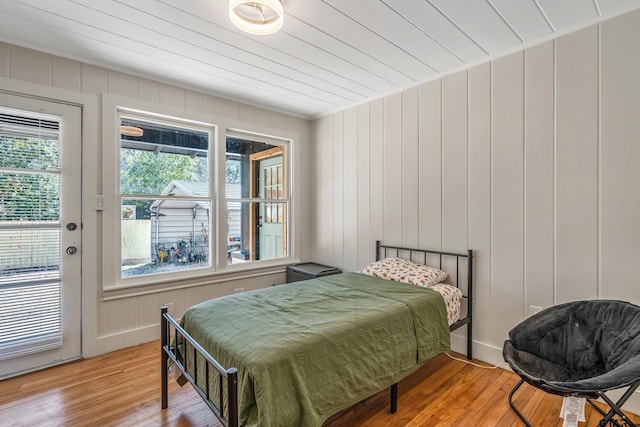 bedroom featuring access to outside, light wood-type flooring, wood ceiling, and baseboards