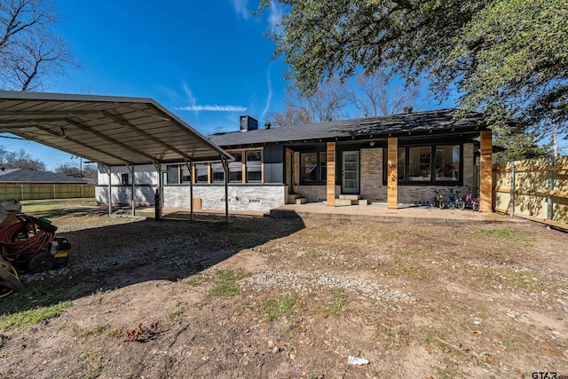 back of property featuring driveway, a detached carport, fence, and a chimney