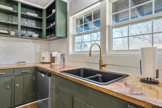 kitchen featuring open shelves, decorative backsplash, a sink, green cabinetry, and dishwasher