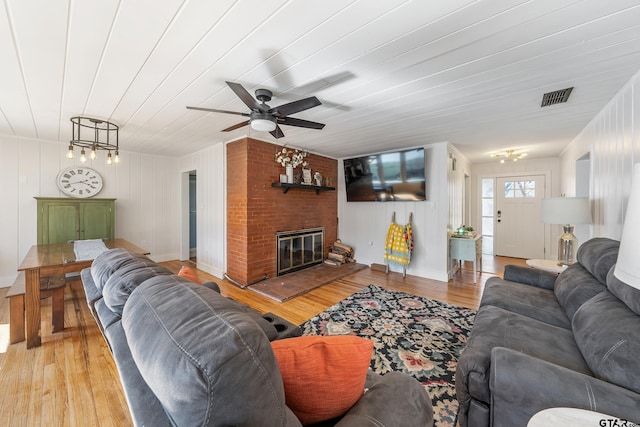 living area with light wood finished floors, a fireplace, and visible vents