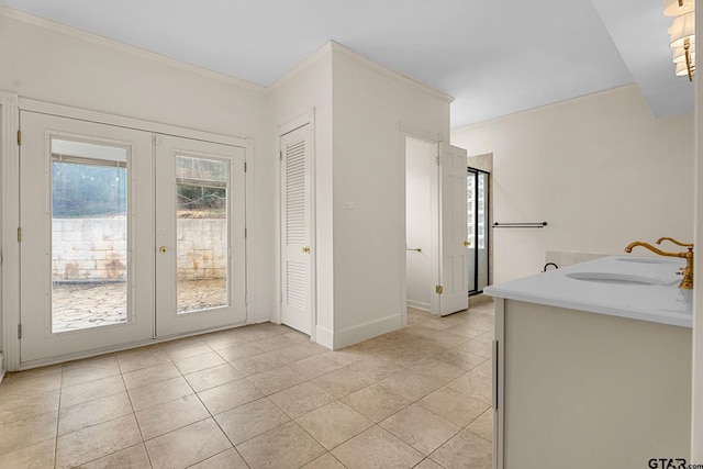 interior space featuring french doors, ornamental molding, sink, and light tile patterned floors