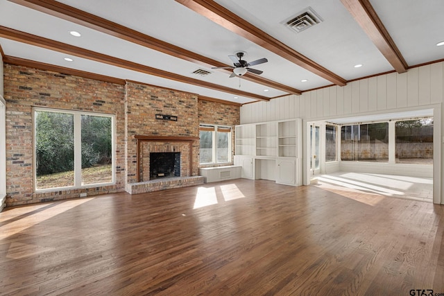 unfurnished living room featuring brick wall, a brick fireplace, hardwood / wood-style floors, and beam ceiling