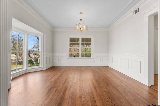 unfurnished dining area featuring ornamental molding, wood-type flooring, and a chandelier