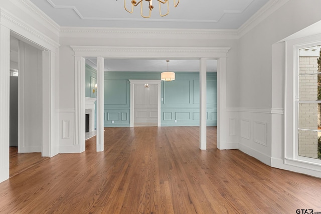 unfurnished living room featuring ornamental molding, a chandelier, and wood-type flooring