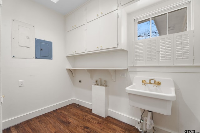 clothes washing area featuring electric dryer hookup, dark hardwood / wood-style flooring, electric panel, and cabinets