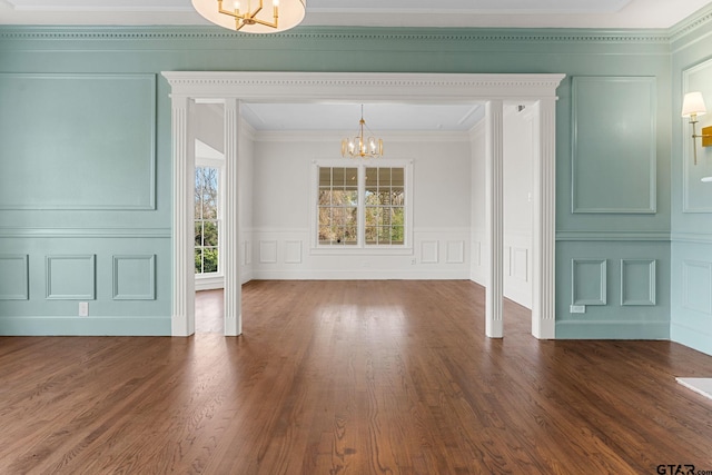 unfurnished dining area featuring ornamental molding, dark hardwood / wood-style floors, a wealth of natural light, and a notable chandelier